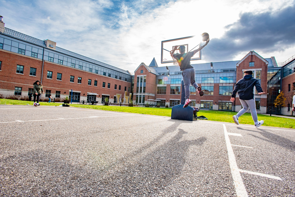 Students playing basketball outside in the Courtyard at the Waterbury Campus.