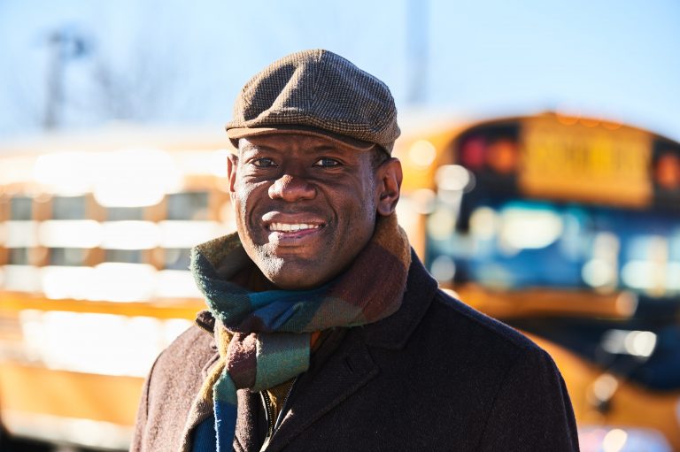 UConn Professor Preston Green, an expert on education and law, stands in front of a school bus.