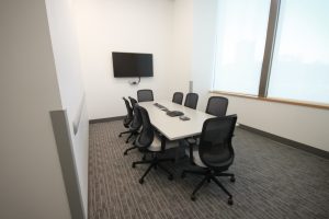 Gray table with eight chairs positioned around it.