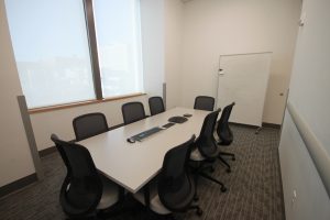 Gray table with eight chairs positioned around it.