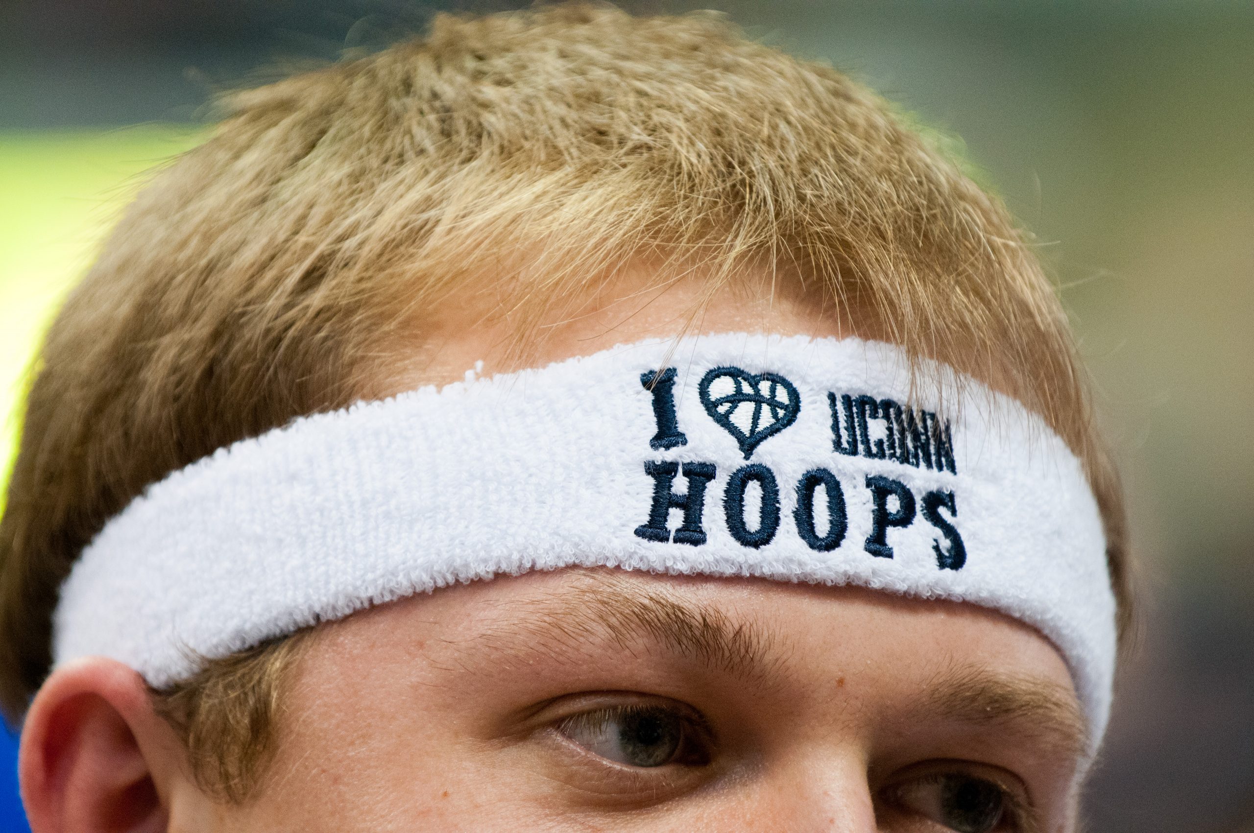 A close-up of a student fan wearing a white headband that says "I love UConn hoops."